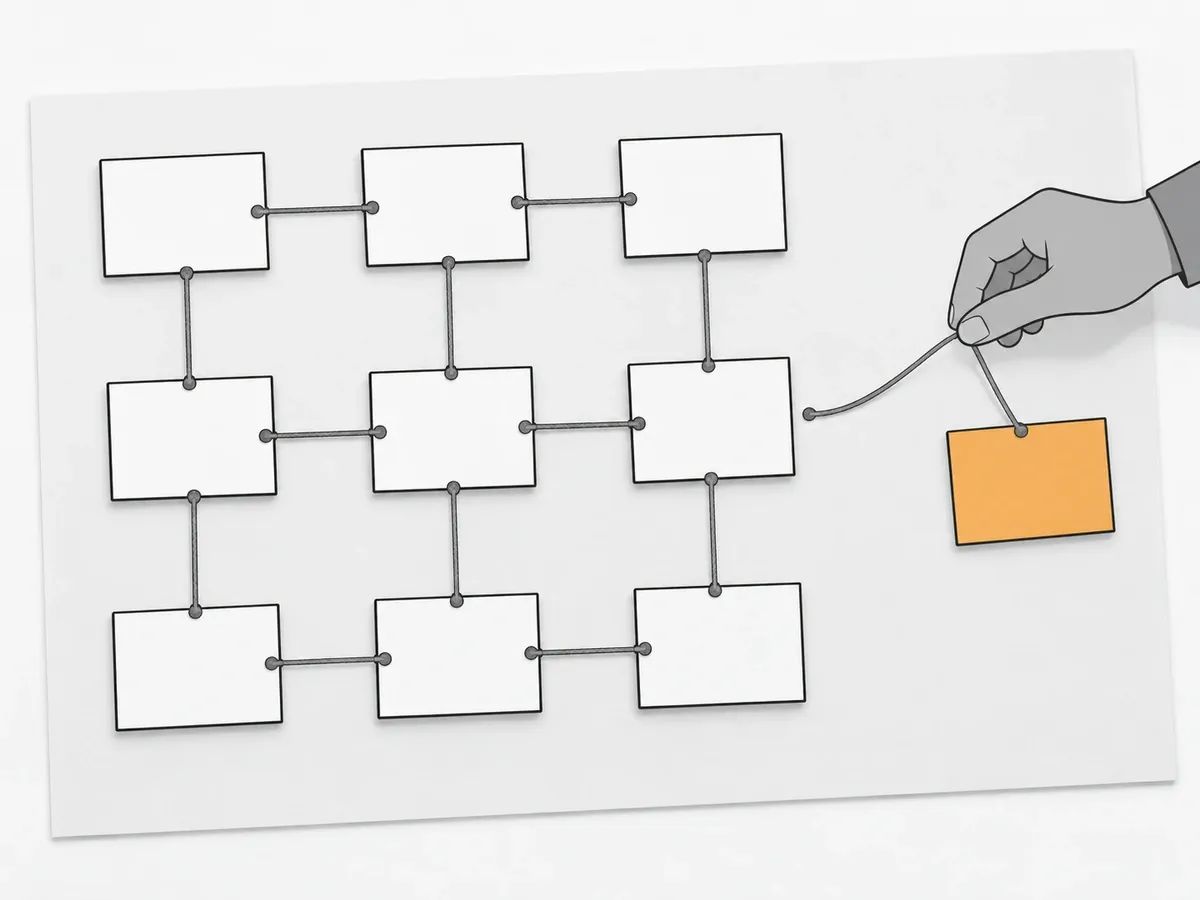 Nine blank cards joined by string on a sheet and a hand laying string towards a tenth, orange card that sits apart